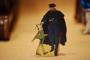 Pinocchio mit Carabiniere, flachschnittige Holzfigur aus der Reihe 'Die Abenteuer des Pinocchio'.