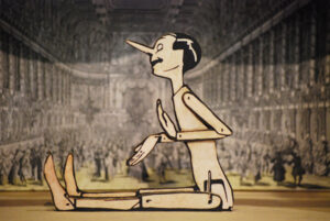Pinocho sentado, figura grande, dibujo pegado a madera y perforada a mano de la novela Las aventuras de Pinocho